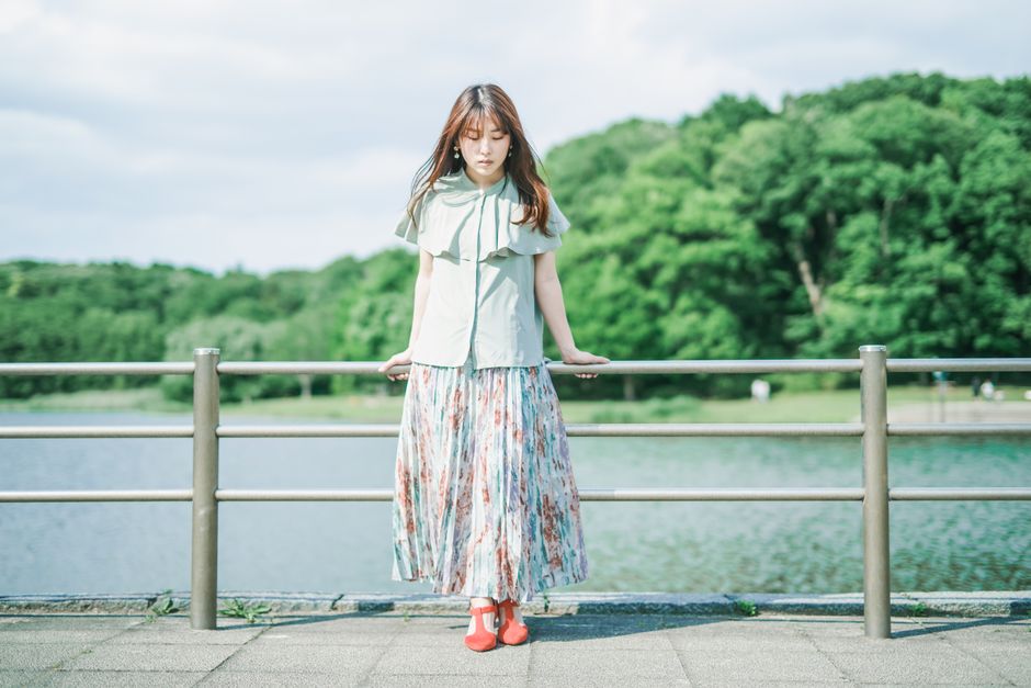 晴れた日に穏やかな湖のそばに立つ花柄のドレスを着たエレガントな女性。